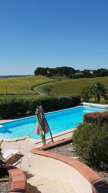 - une piscine avec un parasol à côté d'un champ dans l'établissement Villa au calme avec vue, à Colayrac-Saint-Cirq