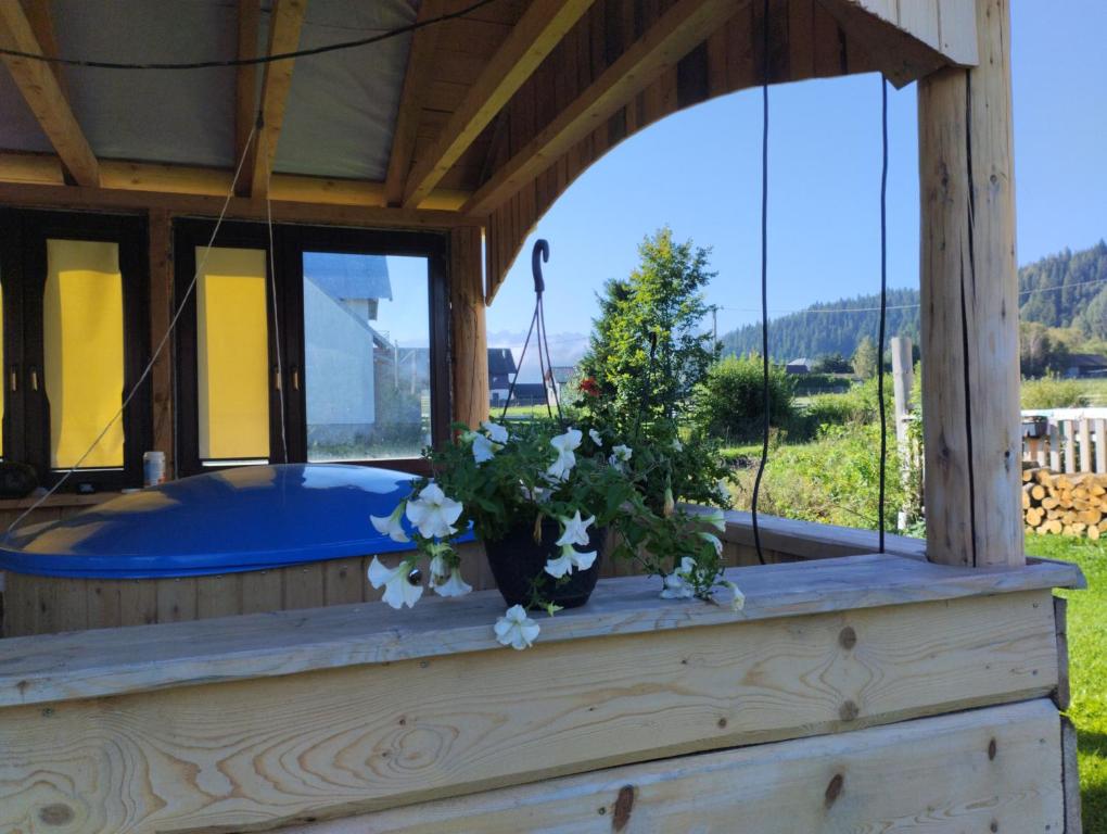 a hot tub in a wooden house with flowers on a porch at Apartament Drewniana Hata in Kacwin