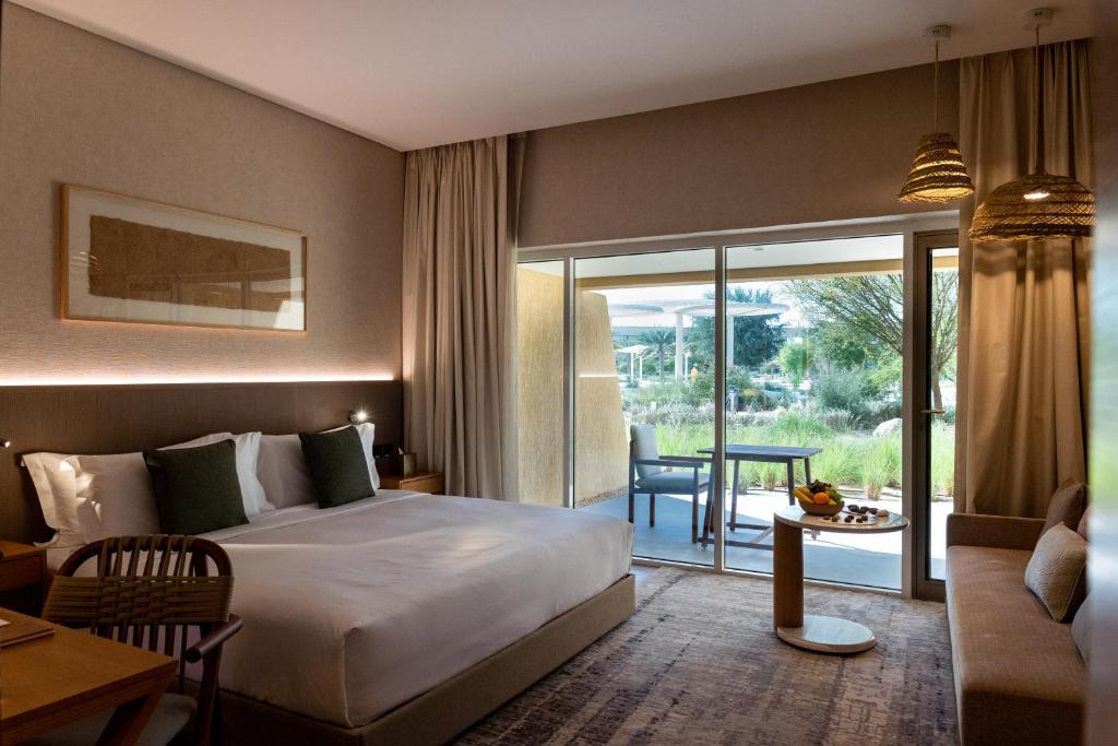 a hotel room with a large bed and a balcony at ERTH Abu Dhabi Hotel in Abu Dhabi