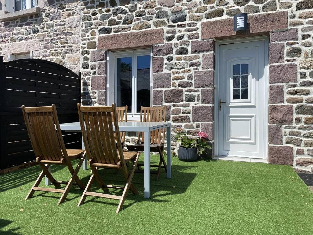 une table et des chaises sur une pelouse devant un bâtiment dans l'établissement 207 - Jolie maison mitoyenne entre terre et mer en campagne de Plurien, à Plurien