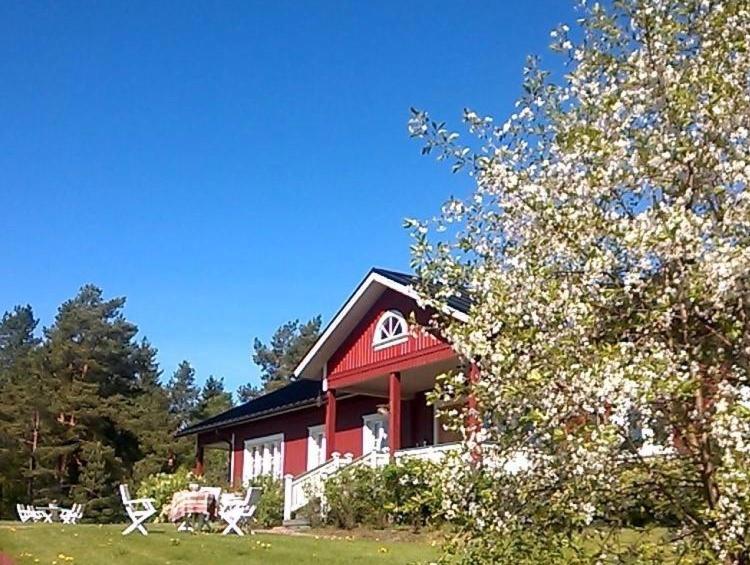 a red and white house with chairs and a tree at Westerby Gård in Inkoo