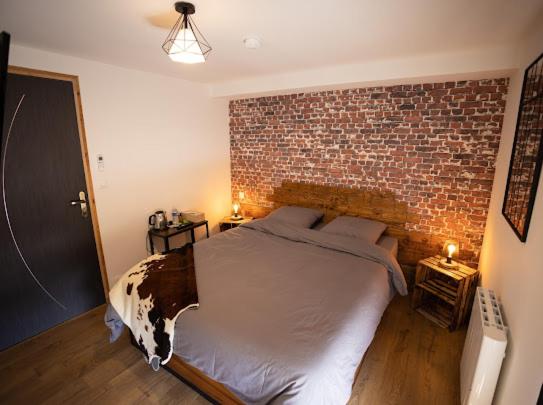 um quarto com uma cama grande e uma parede de tijolos em L’Auberge de papa 