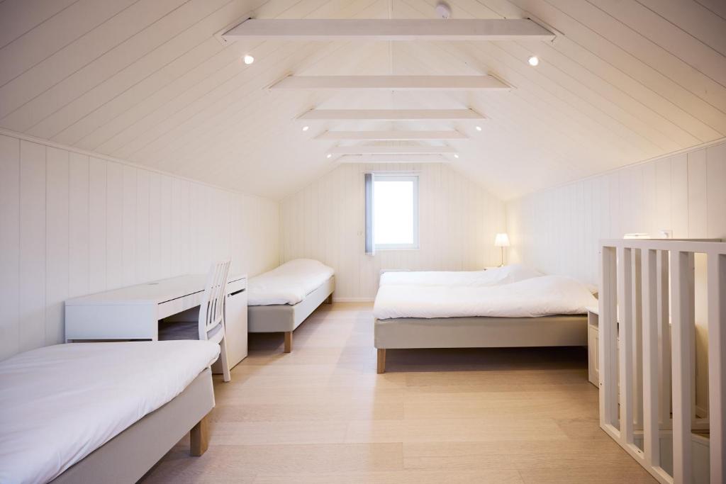 a white room with two beds and a window at Haludden in Stora Dyrön
