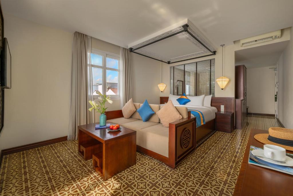 Habitación de hotel con cama y sofá en Royal Riverside Hoi An Hotel & Spa, en Hoi An