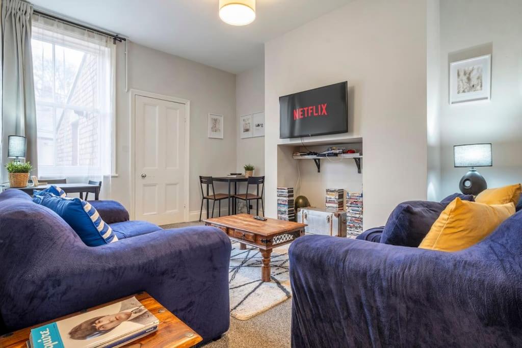 a living room with two blue couches and a table at Beautiful Apartment with Parking in Hexham
