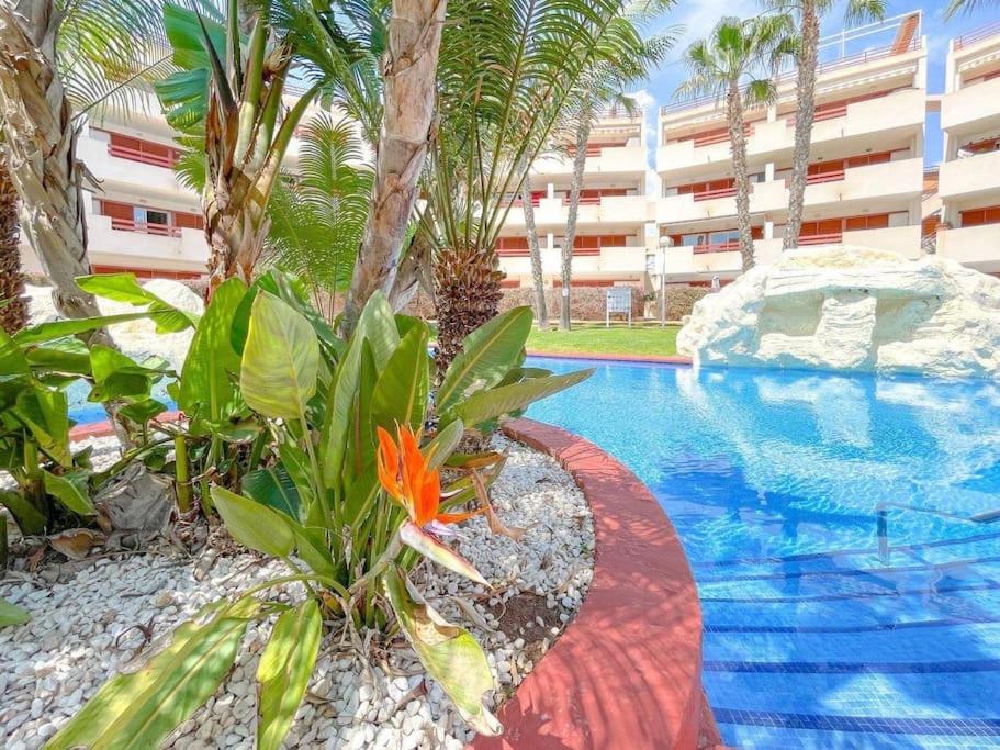 una piscina con palmeras y un gran edificio en Casa Malibu El Rincon Pool view Playa Flamenca, en Playa Flamenca