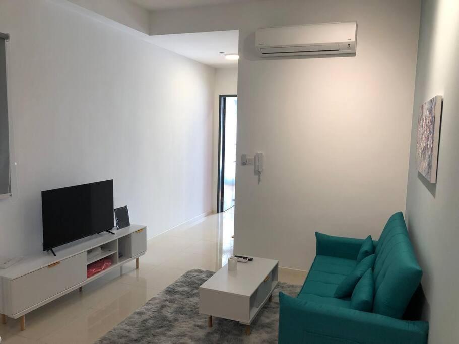 a living room with a green couch and a tv at New Paradigm Residence @1-3/4pax in Johor Bahru