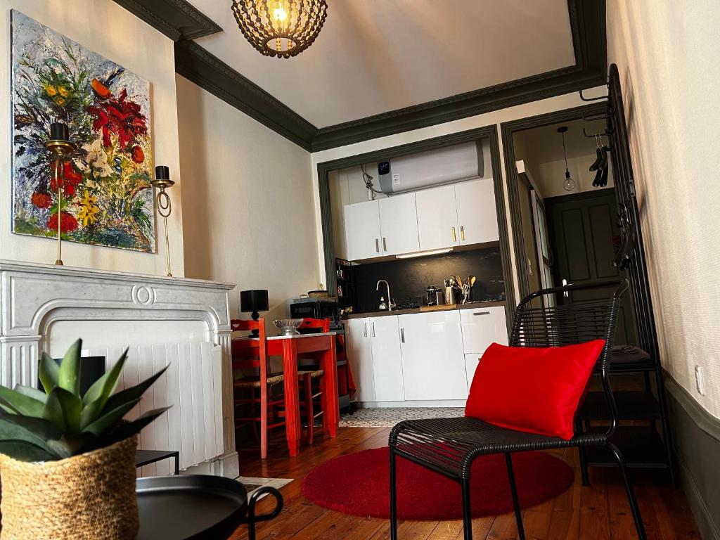 Il comprend un salon avec une chaise rouge et une cuisine. dans l'établissement Chez Frida, au Puy-en-Velay