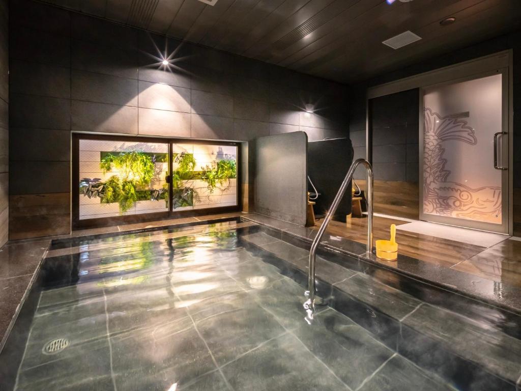 Super Hotel Nagoya Shinkansenguchi في ناغويا: حمام به مسبح والنباتات على الحائط