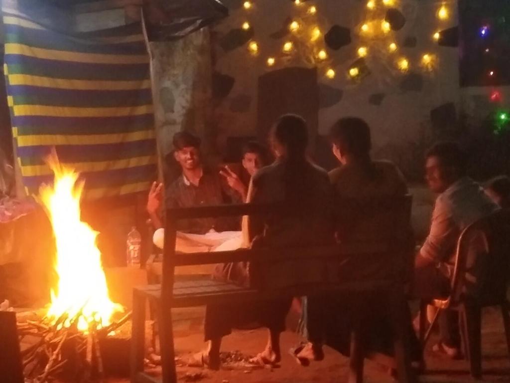 Munnar green portico cottage في مونار: مجموعة من الناس يجلسون حول النار