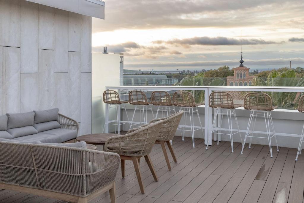 einen Balkon mit Stühlen, Tischen und einer Bar in der Unterkunft Petit Palace Vargas in Sevilla