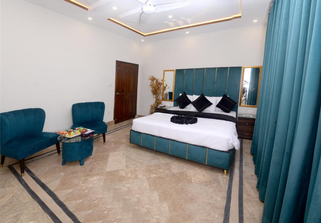 a bedroom with a bed and two blue chairs at Hotel Five Season Lahore in Lahore