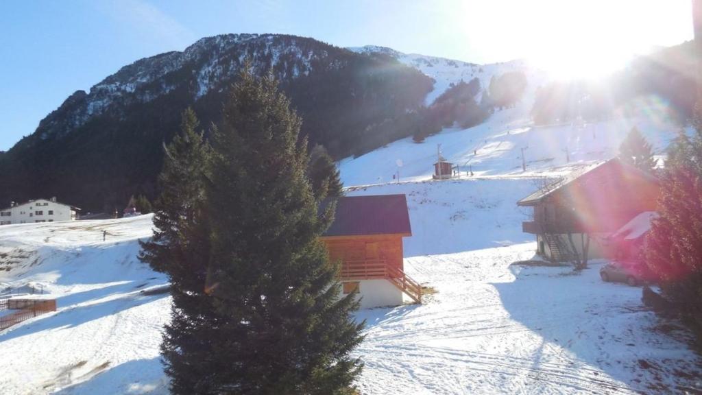 a snow covered mountain with a building and a tree at Duplex station alpe du grand serre in La Morte
