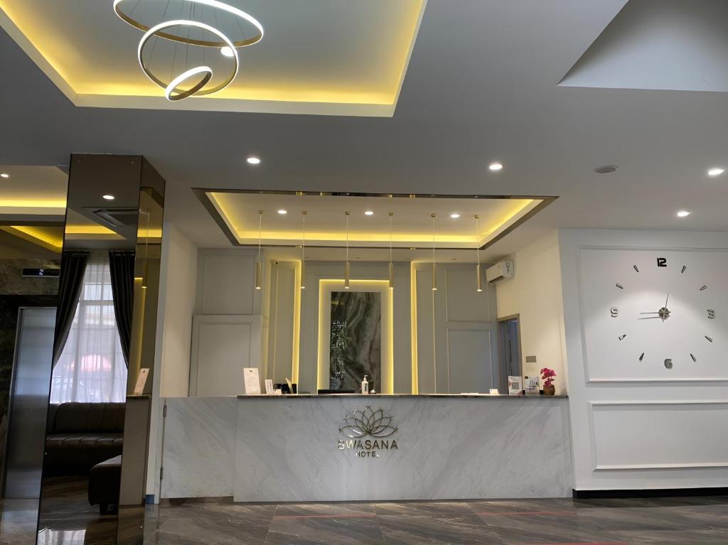 a lobby with a counter with a clock on the wall at Swasana Hotel Medan in Medan