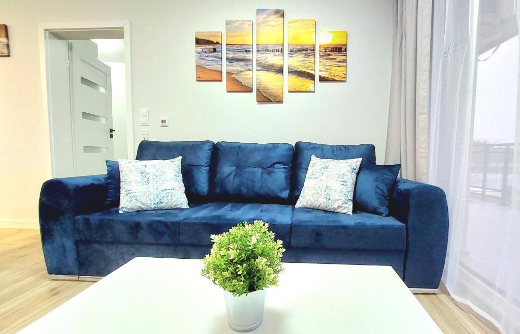 a blue couch in a living room with a table at Apartament Perła Jantaru by TriApart in Jantar