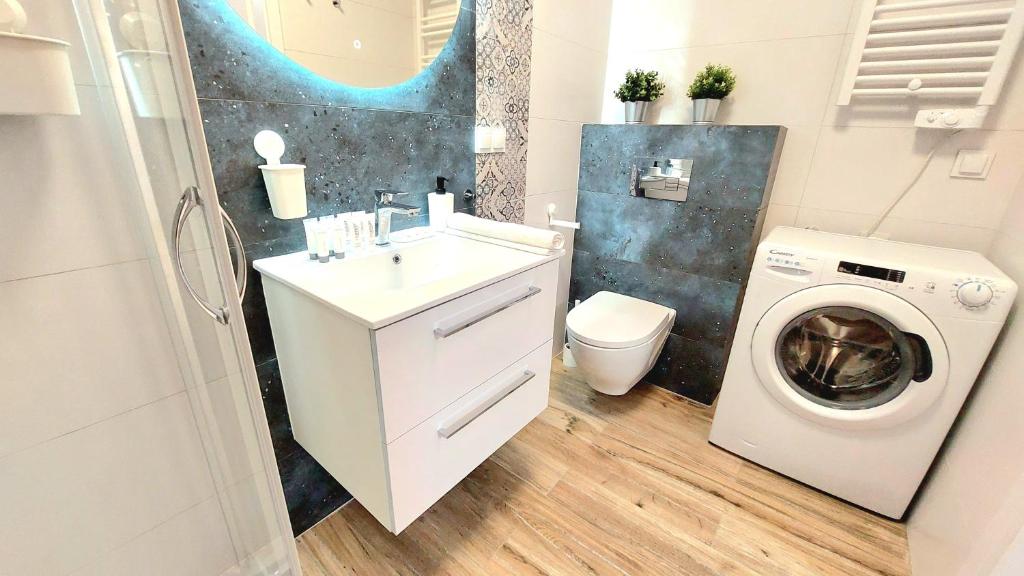 a bathroom with a sink and a washing machine at Apartament Perła Jantaru by TriApart in Jantar