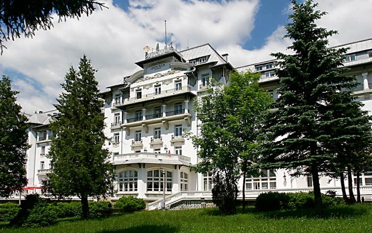 a large white building with trees in front of it at Hotel Palace in Sinaia