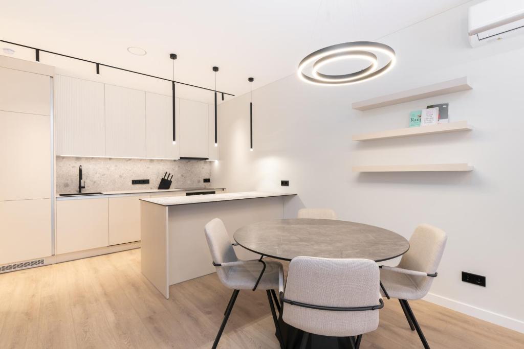 a kitchen with white cabinets and a table and chairs at Hygge Sand Apartment in Vilnius
