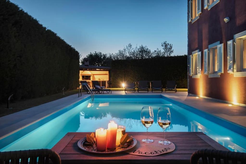 una mesa con velas y copas de vino junto a la piscina en Villa Rahela by Istrialux, en Štokovci
