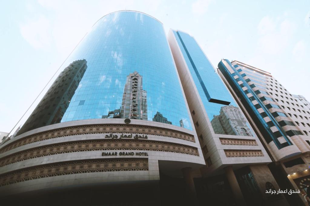 un edificio de cristal alto con un reflejo de un edificio en Emaar Grand Hotel en Makkah