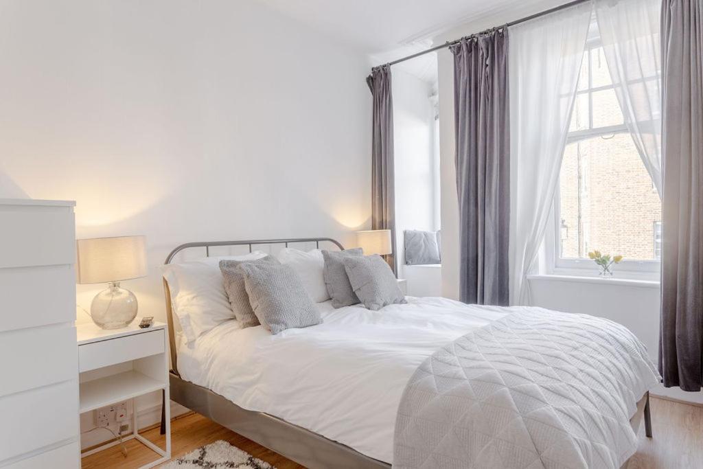 biała sypialnia z łóżkiem i oknem w obiekcie Glenmore Suites w Londynie