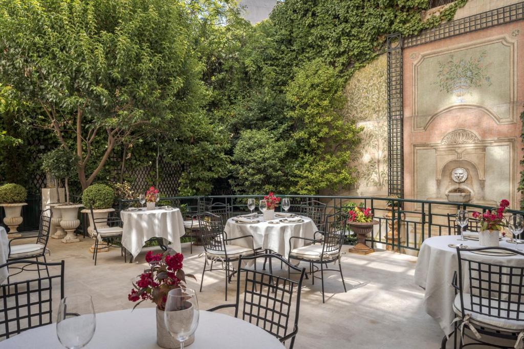 Relais & Châteaux Hotel Orfila في مدريد: فناء في الهواء الطلق مع طاولات وكراسي وأشجار
