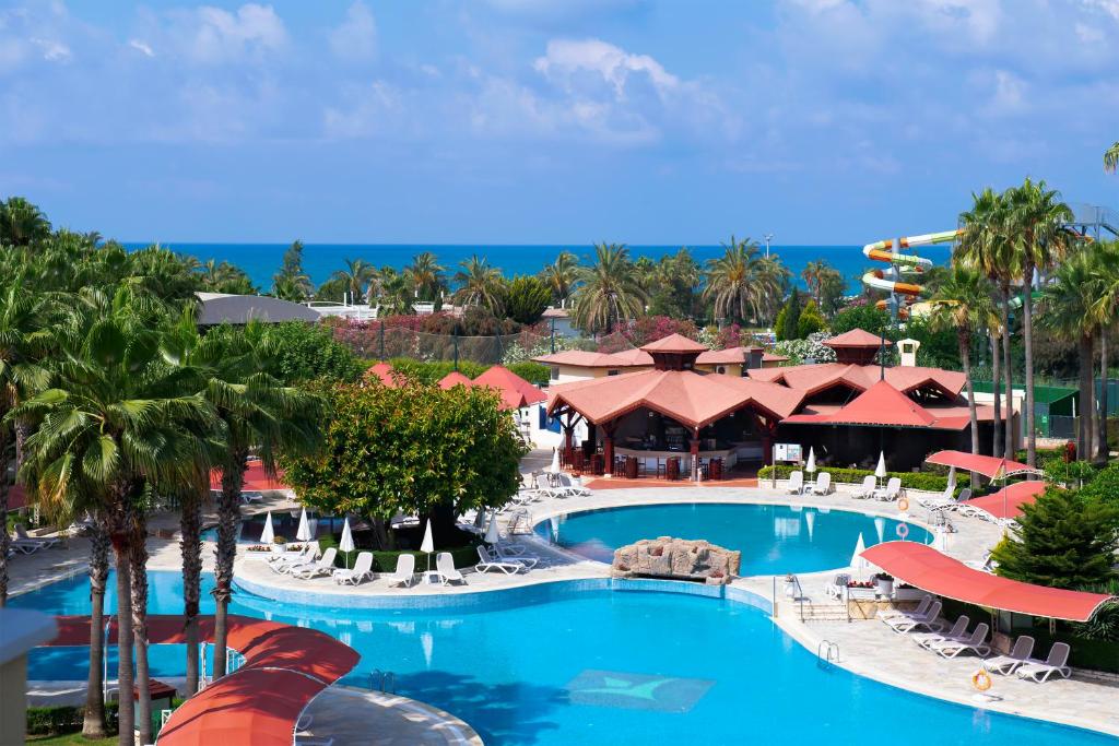 - une vue sur la piscine du complexe avec des chaises et des tables dans l'établissement Miramare Queen Hotel, à Sidé