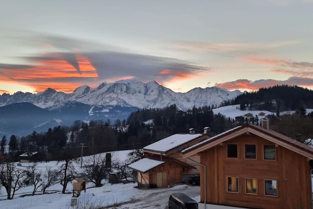 une maison dans la neige avec des montagnes en arrière-plan dans l'établissement Les Balcons du Mont-Blanc : Appartement centre village, à Cordon