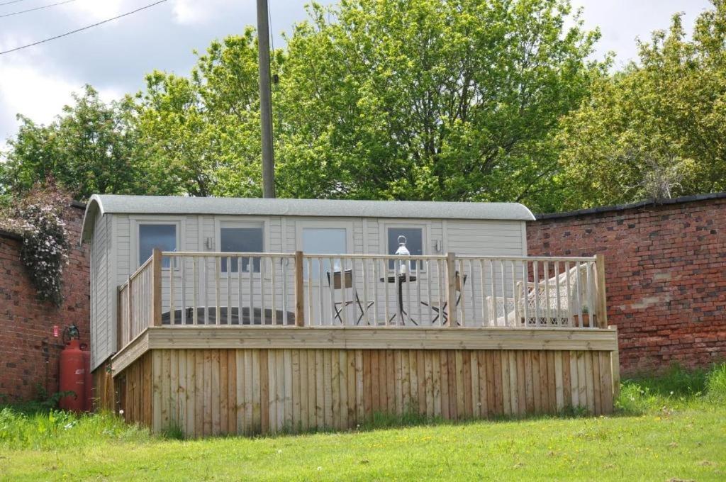 a house with a deck and a fence at Shepherd's Hut at Cefn Tilla Court in Usk