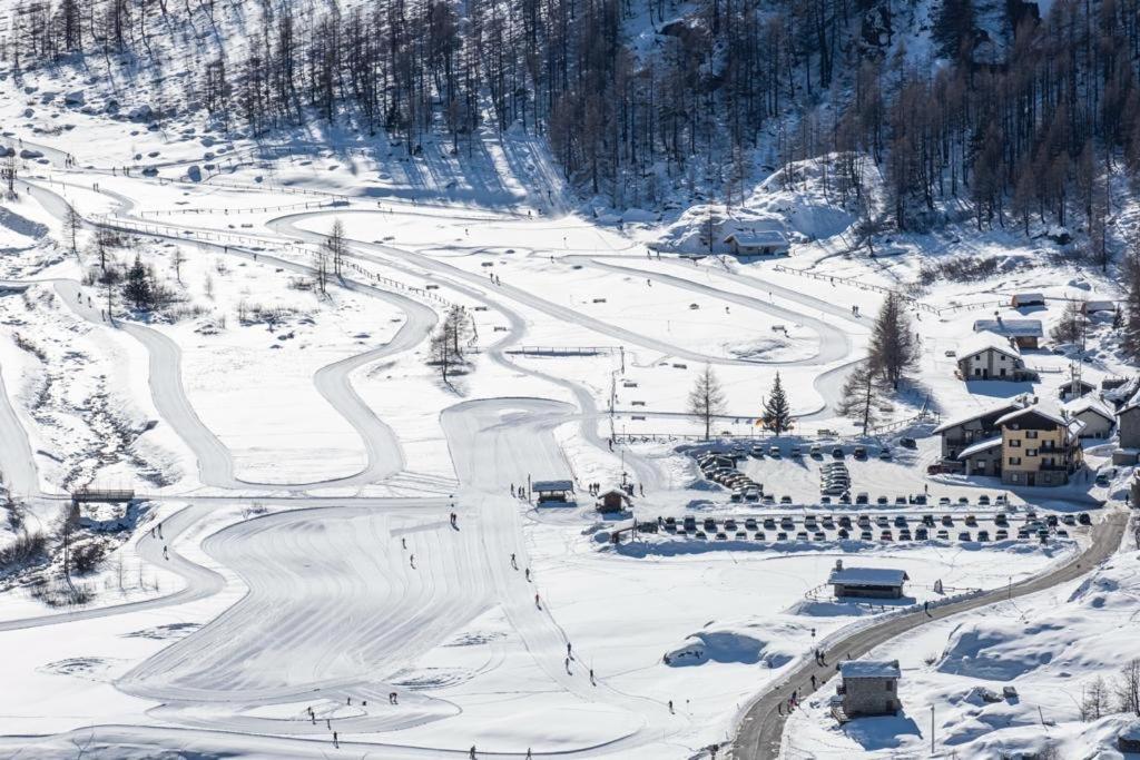 una montaña cubierta de nieve con una pista de esquí con casas en Albergo Gran Paradiso en Valsavarenche