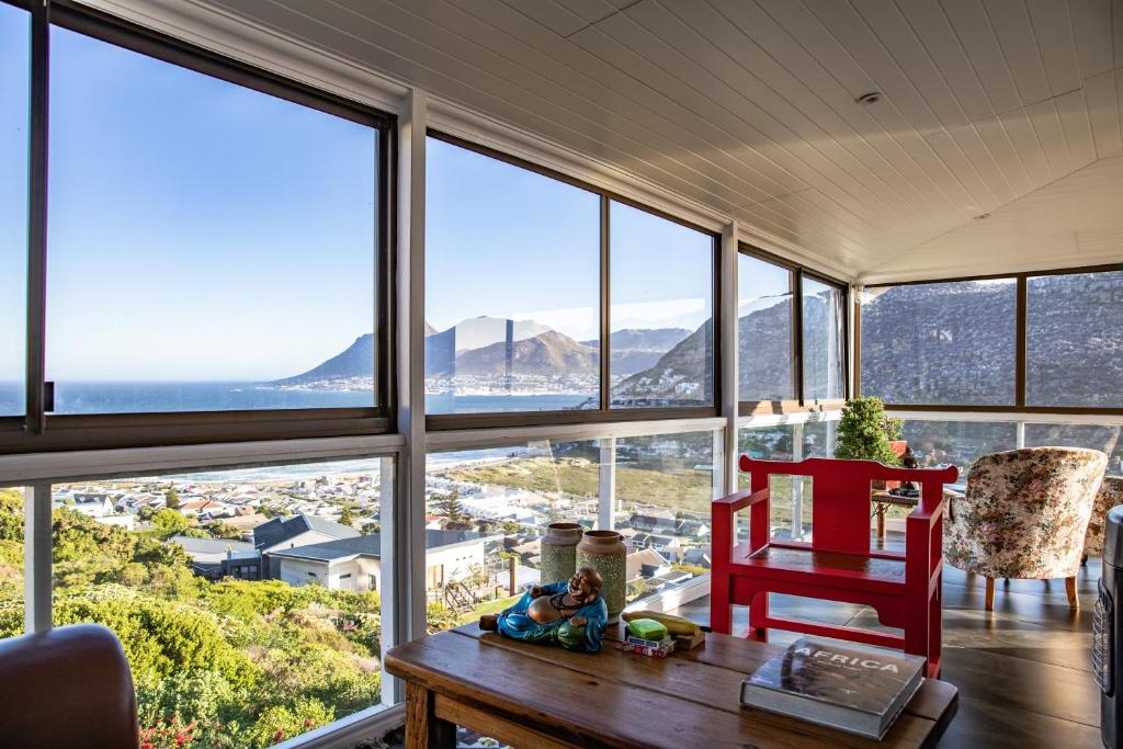 um quarto com uma mesa, uma cadeira e janelas em Mettahouse na Cidade do Cabo