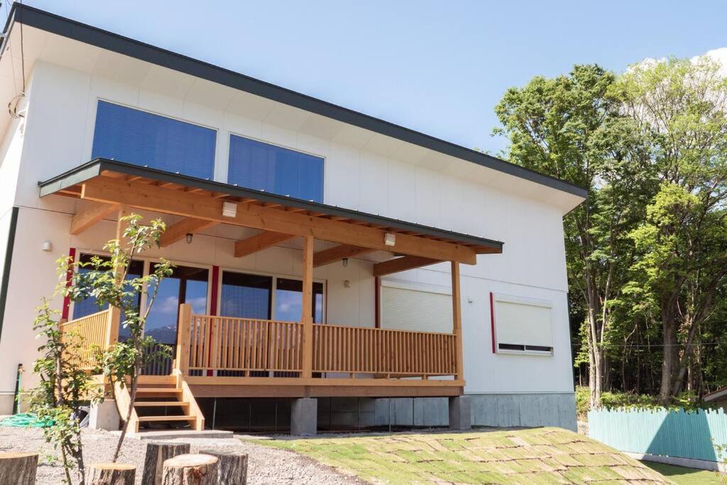 a house with a balcony with blue windows at 山が見える貸切コテージ「WIND+HORN」 
