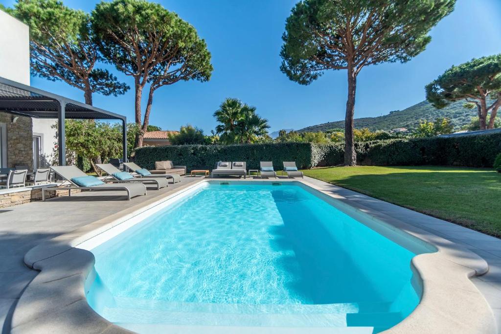 - une piscine avec des chaises longues à côté d&#39;une maison dans l&#39;établissement Domaine Villas Mandarine Private Pools &amp; Spa, à Calvi