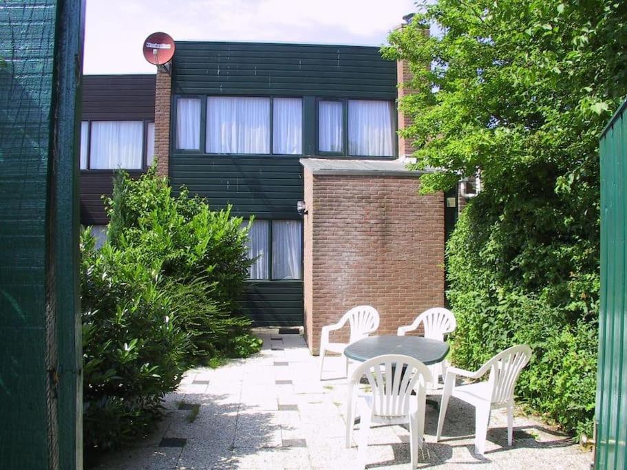 um pátio com uma mesa e cadeiras e um edifício em Lepelblad 37* em Nieuwvliet