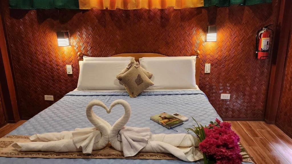 a bed with two towels in the shape of a heart at Flores Garden Hotel in Coron