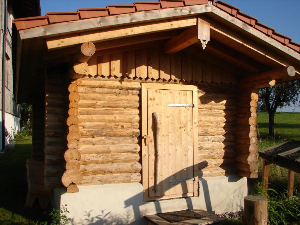a wooden shed with a roof on top of it at Blockhaus im Permakulturgarten in Argenbühl