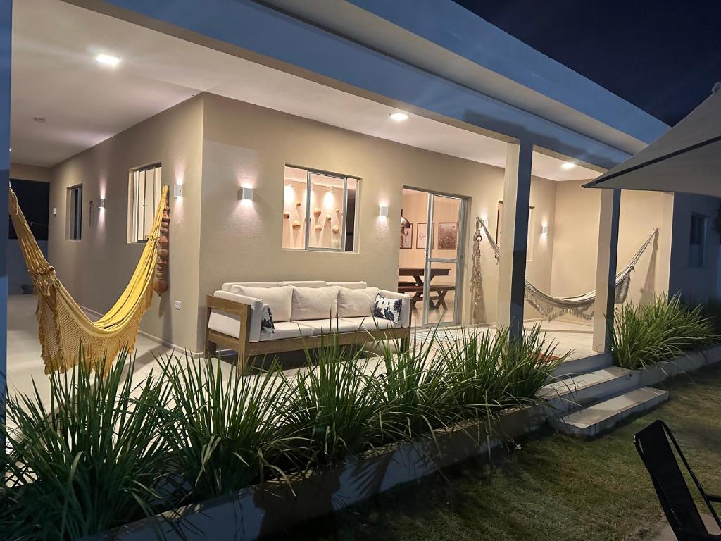 a bedroom with a hammock and a house at Casa Recanto dos Guaiamuns - Carneiros PE in Sirinhaém