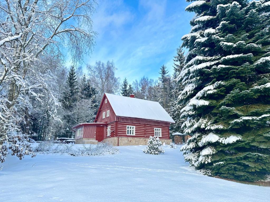 a red barn with a snow covered roof in the snow at Chalupa Janovice in Rudník