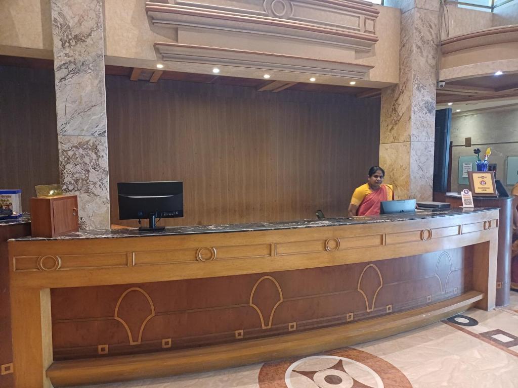 Eine Frau, die an einem Tresen in einer Lobby sitzt. in der Unterkunft Hotel Benzz Park Chennai in Chennai