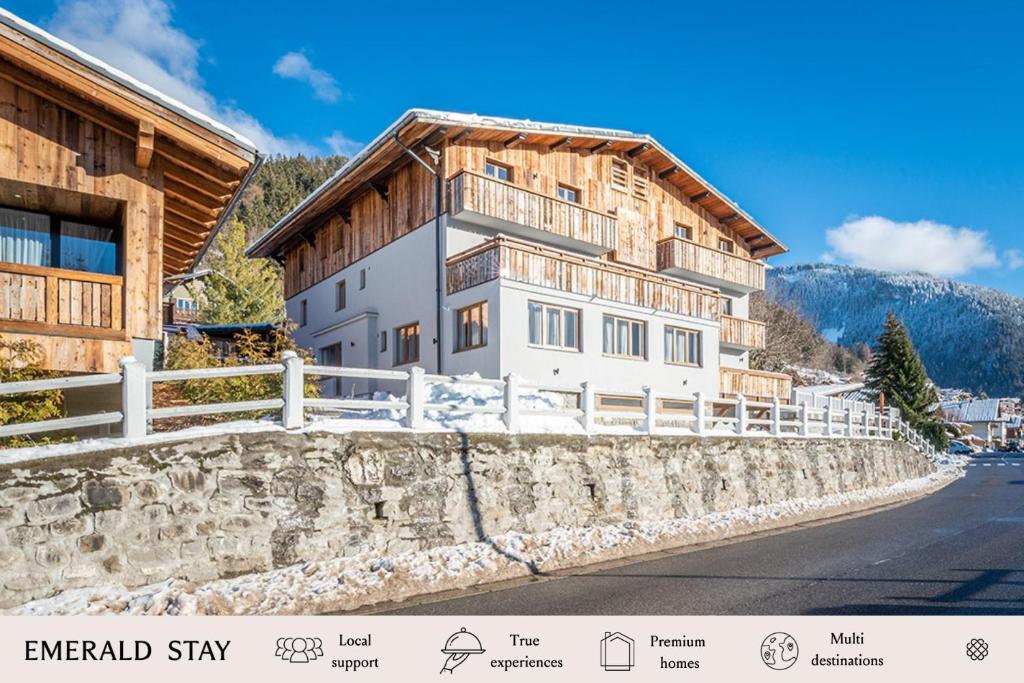 a house with a wooden roof on a stone wall at Emerald Stay Apartments Morzine - by EMERALD STAY in Morzine
