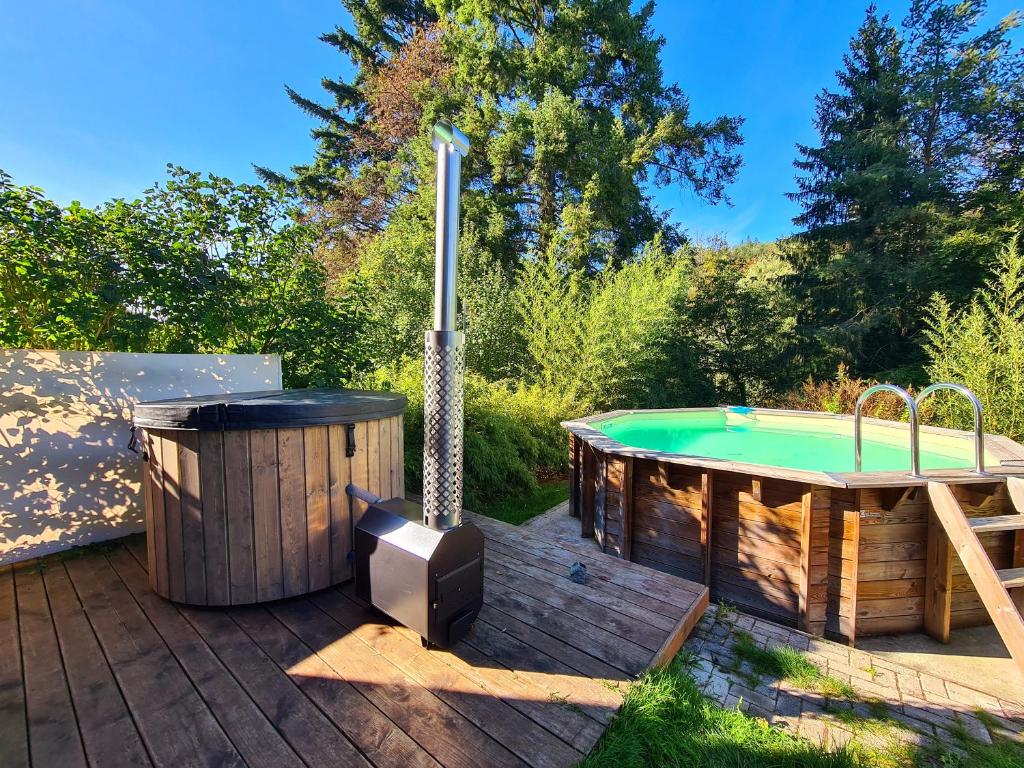 una bañera de hidromasaje en una terraza junto a un jacuzzi en Le Chalet Cosy piscine et spa, en Weiterswiller