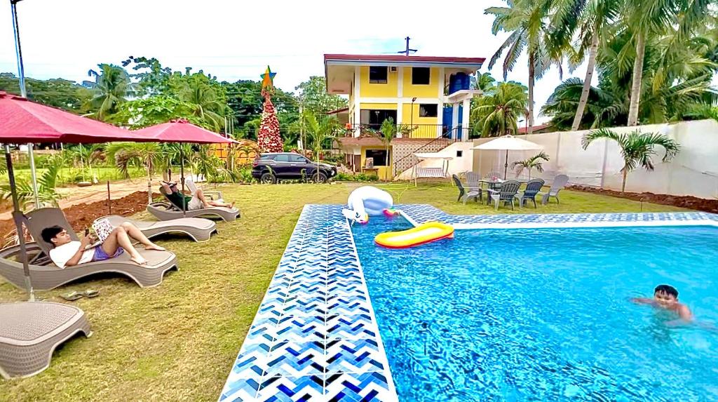 a swimming pool with people sitting in chairs next to a house at Villa Lourdes Resort in Panglao