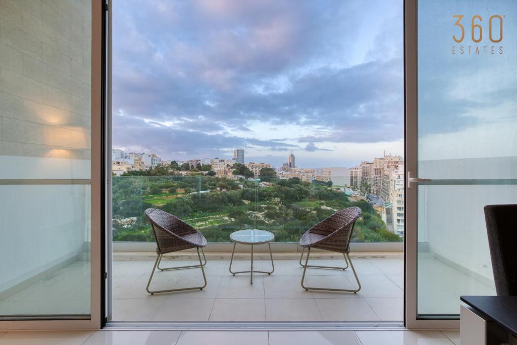 Un balcón con 2 sillas y una mesa frente a una ventana en A fully equipped 3BR home with lovely views & WIFI, en San Julián