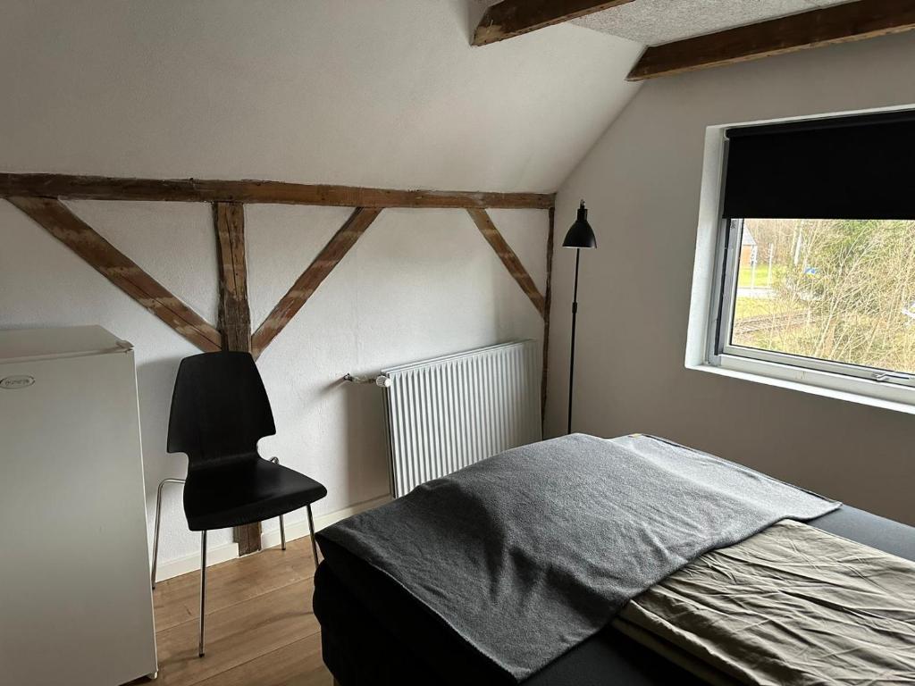 a bedroom with a bed and a window and a chair at Den gammel togstation in Give