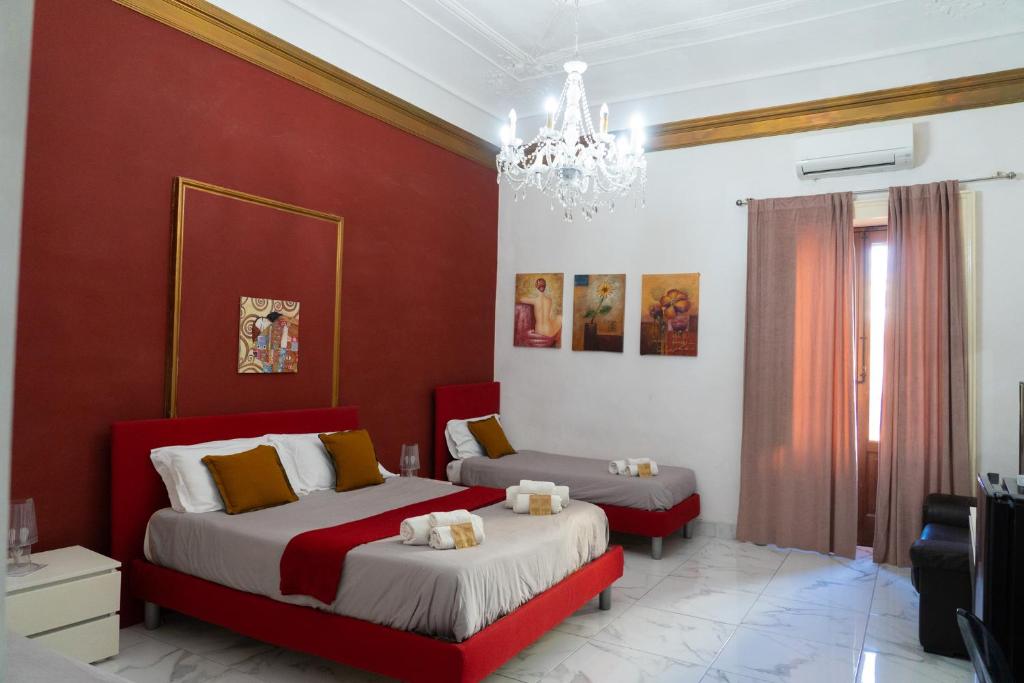 a bedroom with two beds and a chandelier at B&B Opera in Catania