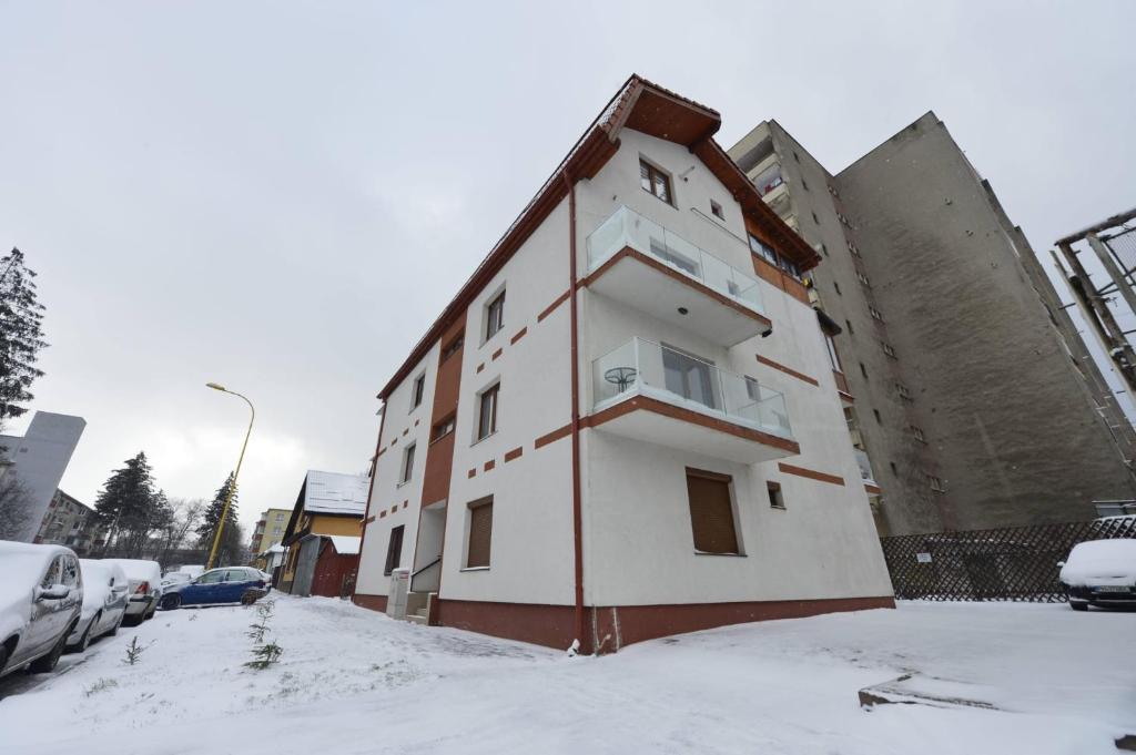un edificio con nieve en el suelo delante de él en Apartament Astra BN70, en Brasov