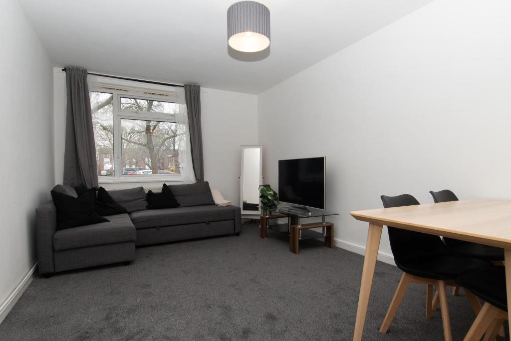 a living room with a couch and a television at Modern 1 bed flat on the outskirts of Kingston in Teddington