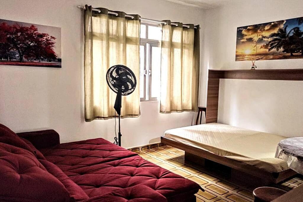 a bedroom with a bed and a fan next to a window at Studio pé na areia, confortável, wi-fi, av. Praia in Santos