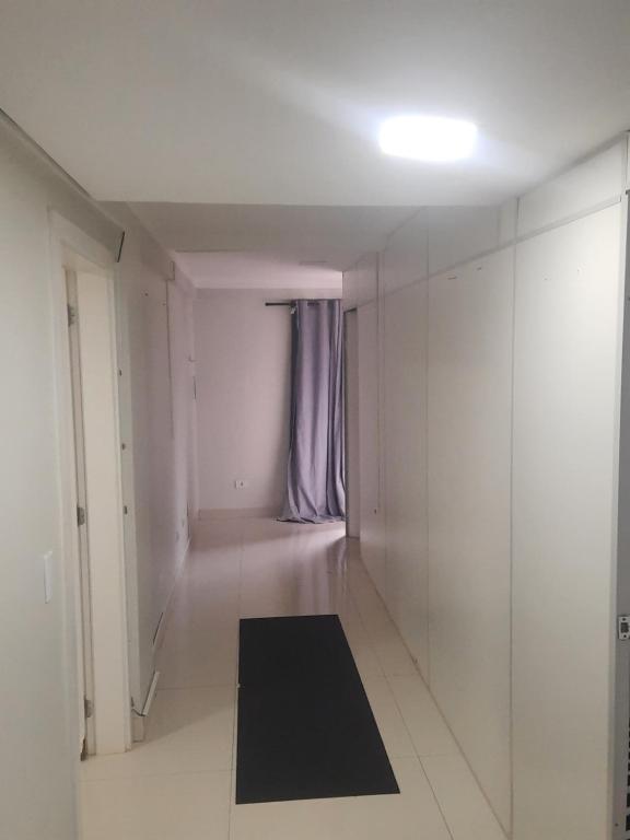 a white hallway with a black rug on the floor at VS HOSPEDAGEM in Cascavel