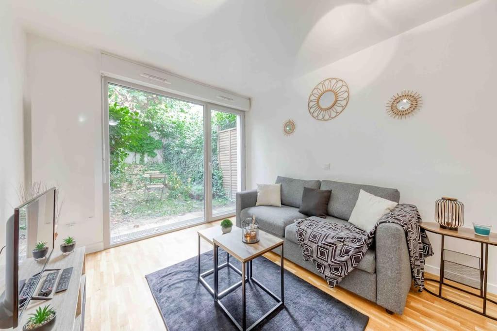 ein Wohnzimmer mit einem Sofa und einem Tisch in der Unterkunft Appartement moderne, Metro 7, Parking et Jardin in Villejuif
